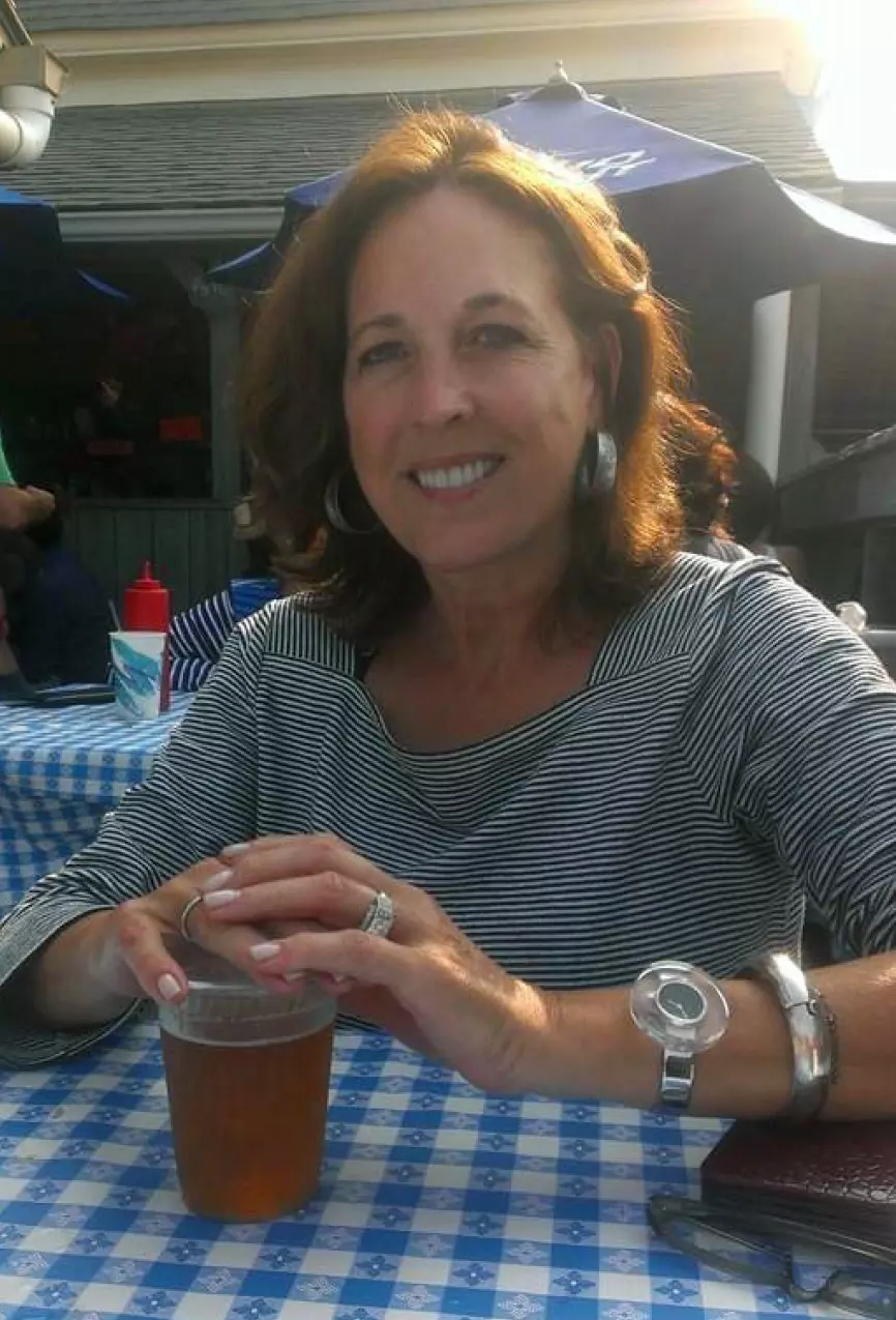 Eidy smiling at an outdoor table set with a blue checkered tablecloth