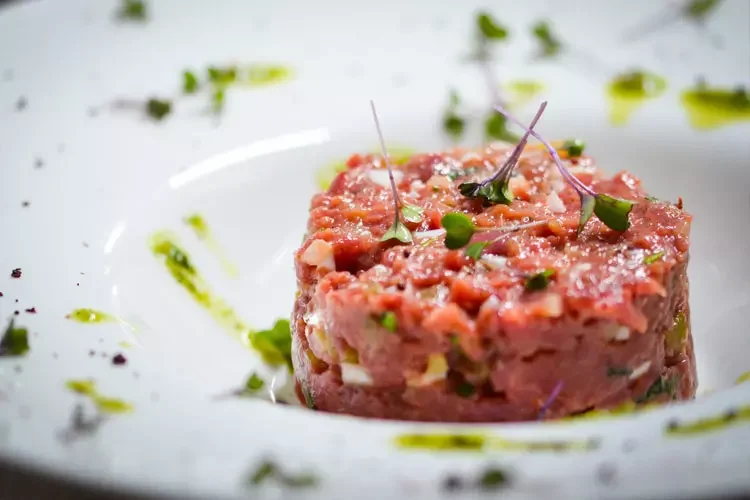 Steak tartare topped with microgreens and herb oil