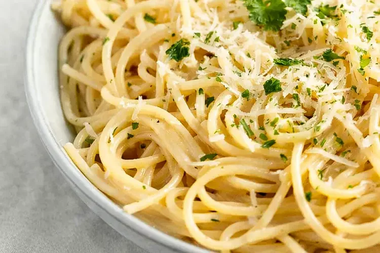 A bowl of thin pasta with grated cheese and parsley
