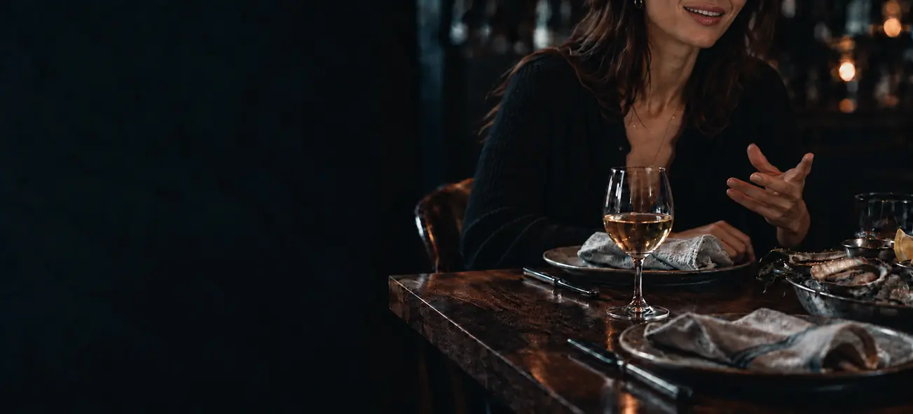 A guest in conversation at a restaurant table set with wine