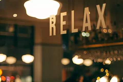 A warmly lit bar with a sign reading RELAX