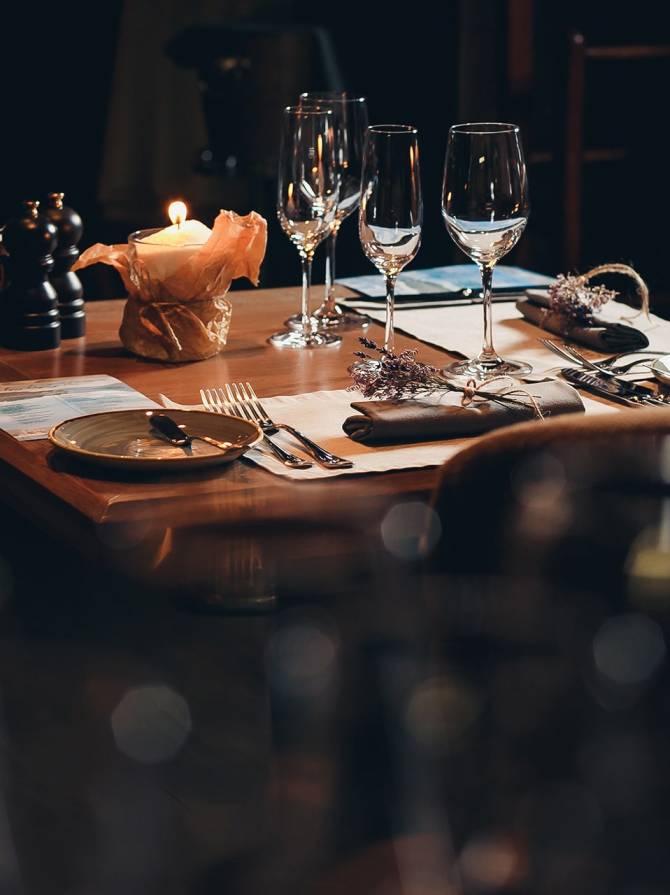 A candlelit restaurant table set with wine glasses, pepper mills and sprigs of lavender
